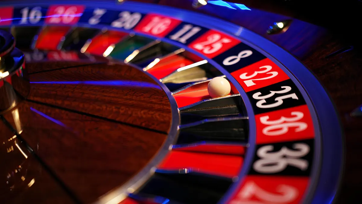 Roda roulette berputar dengan pencahayaan dramatis di meja kasino
